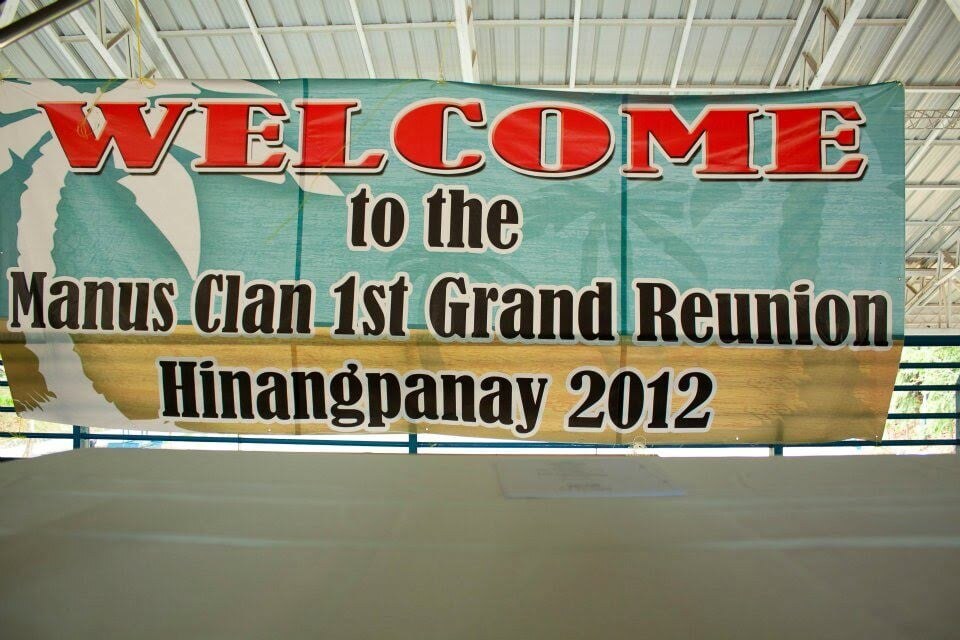 A banner hung under a metal roof, reading "Welcome to the Manus Clan 1st Grand Reunion, Hinangpanay 2012".